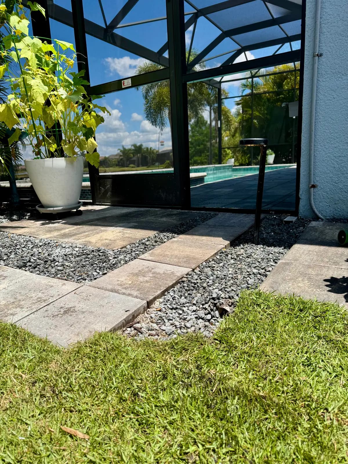 A river rock drainage strip set between pavers and fresh sod